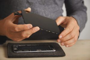 master holds new screen replacement disassembled smartphone his laboratory close up